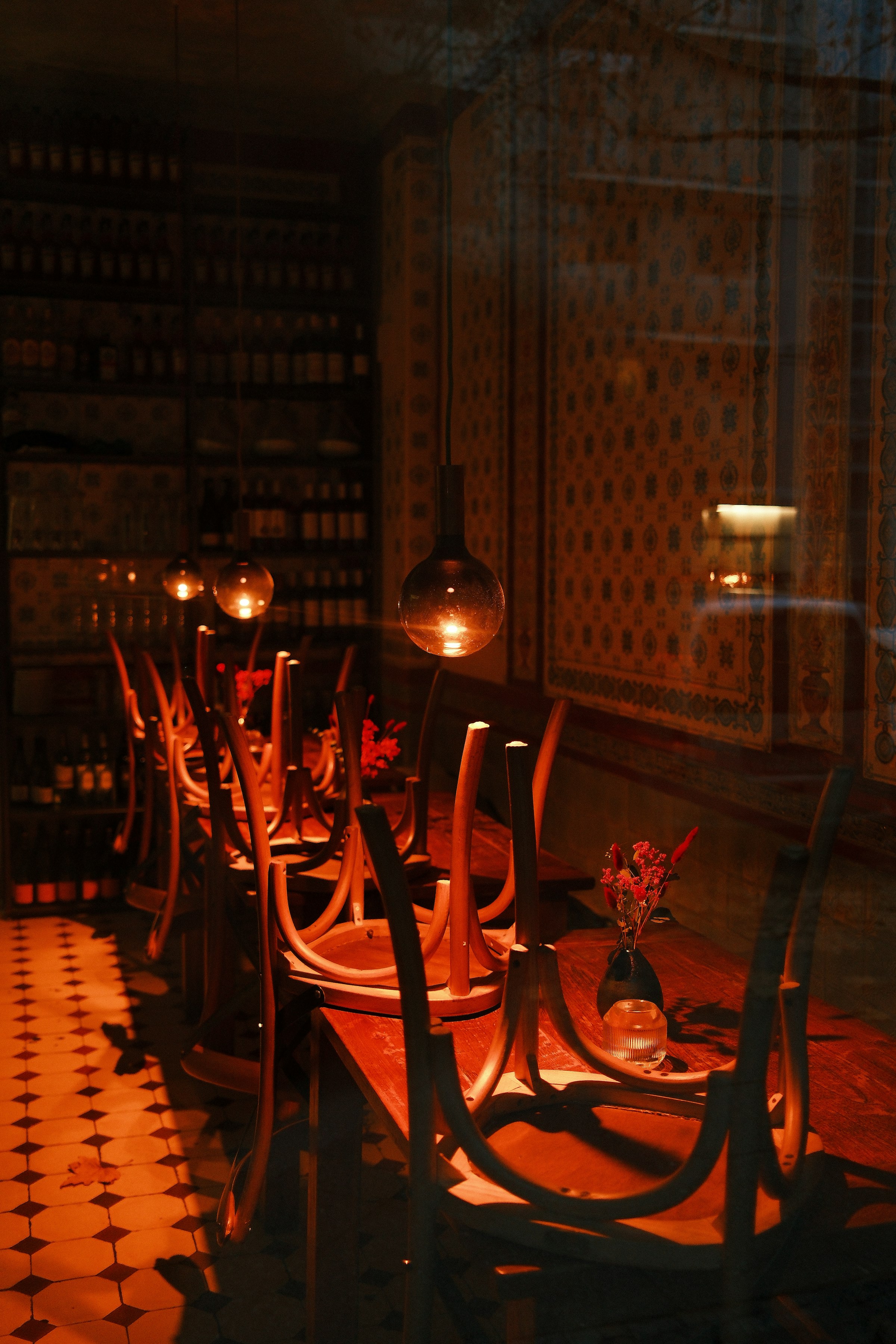 Warm, candlelit dining room with wine bottles along the wall