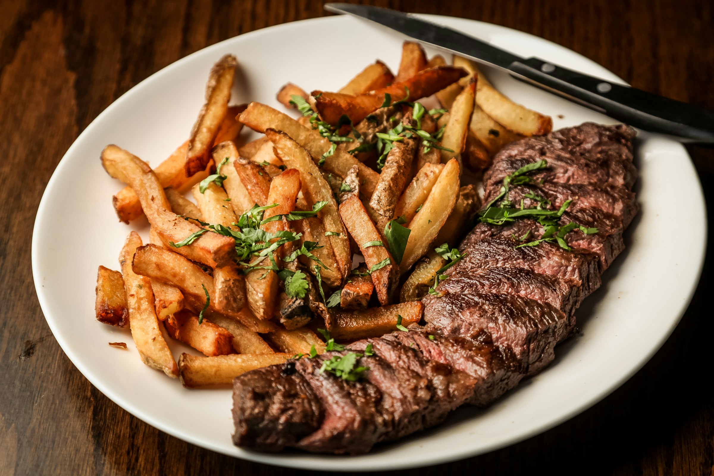 Sliced steak and hand-cut chips on a dark wooden table